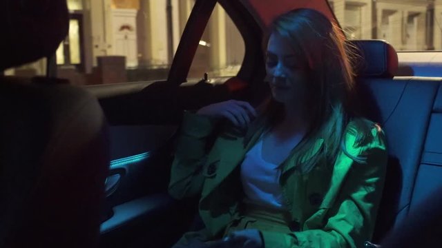 attractive young womanising cell mobile phone in taxi at night