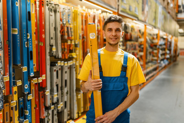 Male builder with building level in hardware store