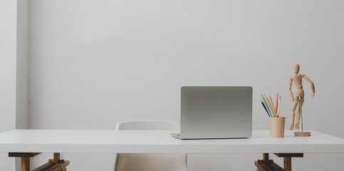 Laptop computer on white table and coffee cup in modern office room with white wall