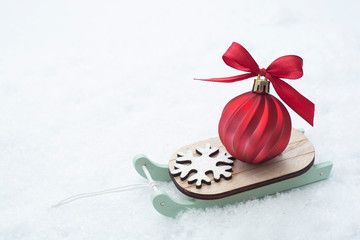 Christmas winter wooden sleigh with red bauble over the snow. Abstract winter greeting card with copy space.