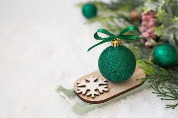 Fototapeta na wymiar Christmas winter wooden sleigh with green bauble over the snow. Abstract winter greeting card with copy space.