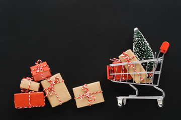 Shopping cart full of various gift boxes and a Christmas tree.