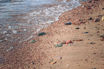 sea wavy shore line waterfront dirt ground with sand and stones background 