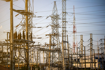 The complicate of wires and cables at the power plants at the roadside in the afternoon or morning with flare. 
