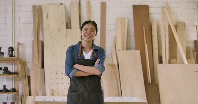 Close-up portrait of young attractive carpenter standing with crossed arms smiling positively into camera. Slow motion