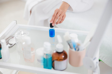 Young woman grabbing bottle of vitamin serum