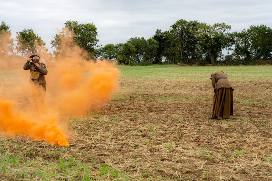 WW1 battle scene depicting a mustard gas attack on British troops, depicted by the orange smoke. A solder puts on a gas mask for protection in the smoke