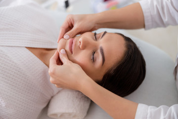Fototapeta na wymiar Masseuse massaging lady chin at spa salon