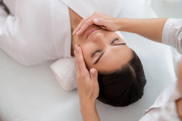 Fototapeta na wymiar Relaxed young woman having face massage at beauty salon