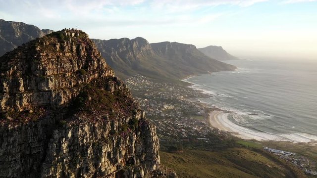 Fly-By Cinematic Aerial Shot of Cape Town's Lions Head Peak Revealing Camps Bay and Table Mountain National Park During Golden Hour Sunset