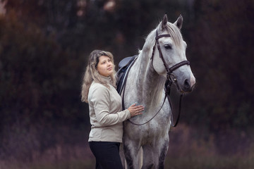 Beautiful girl posing with a purebred arabian horse outdoors. 