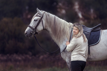 Beautiful girl posing with a purebred arabian horse outdoors. 