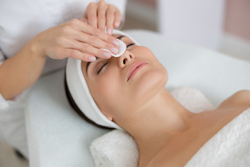 Beautician hands cleaning lady face before the procedure