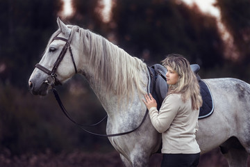 Beautiful girl posing with a purebred arabian horse outdoors. 