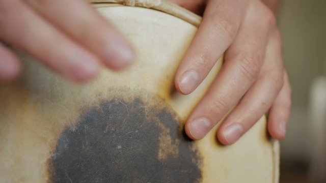 Close up of hands of a man playing a drum.