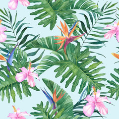Tropical watercolor seamless pattern with exotic hibiscus and strelitzia flowers and leaves on a blue background.