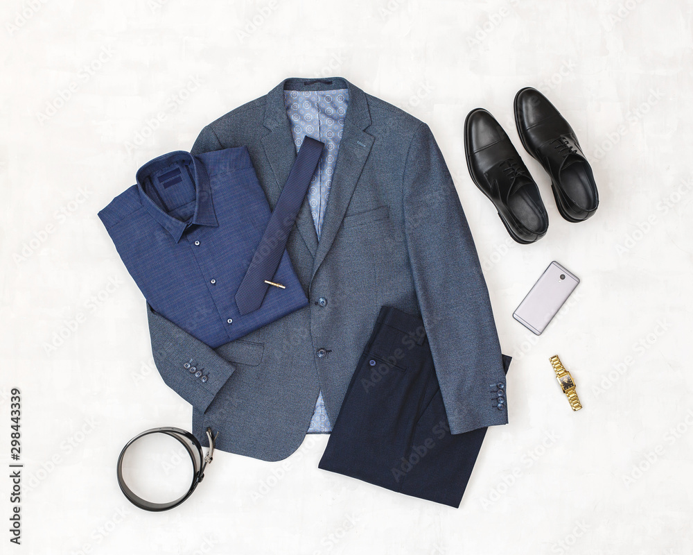 Wall mural Suit jacket, pants, blue shirt, black shoes, belt, watch, necktie, smartphone. Overhead view of classic elegant formal men's outfit. Set of stylish men's clothes and accessories. Flat lay, top view.