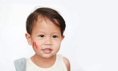Portrait of little Asian baby boy with face make up sticker lesion on face in Halloween costume looking out over white background.