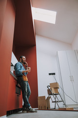 Smiling handyman drinking coffee during home repair