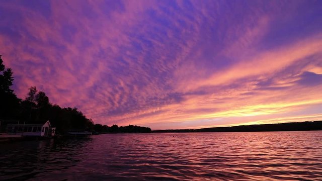 Vivid violet purple sunset over calm water at Silver Lake, NY State, boathouse ob left