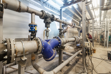 pumping station under construction. pipes of central heating system and water pipes with thermal insulation. Electric motor water pump under repair process at power plant. Industrial zone.
