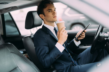 Young driver with coffee and tablet in car stock photo