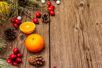 Spirit Christmas background. Fresh mandarins, dog-rose berries, candies, pine branches and cones, artificial snow