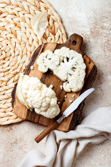 Fresh raw cauliflower sliced into steak on wooden cooking board. Top view, copy space
