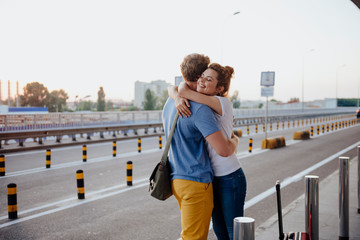 Happy girl hugging boyfriend after arrival from trip stock photo