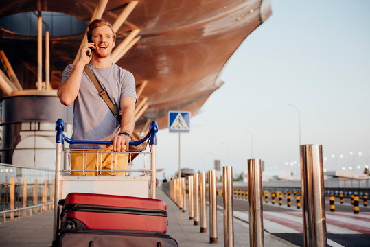 Man With Phone Transporting Luggage To Airport Stock Photo