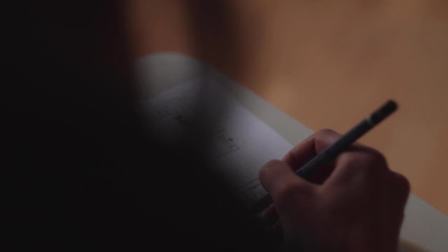 close up di donna di spalle che lavora a un progetto con matita in mano