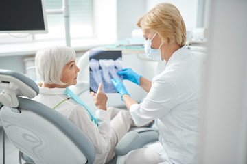 Female patient sitting in dentist chair and looking at the X-ray