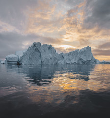 Obraz na płótnie Canvas Arctic nature landscape with icebergs in Greenland icefjord with midnight sun sunset sunrise in the horizon. Early morning summer alpenglow during midnight season. Ilulissat, West Greenland.