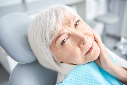 Senior lady experiencing a toothache at dentist room