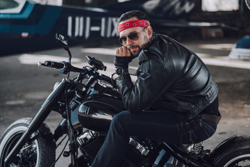 Fototapeta na wymiar Bearded biker sitting on motorcycle in garage