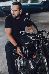 Fototapeta na wymiar Caucasian brutal biker waiting for somebody in garage