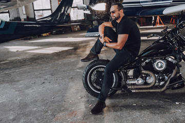 Fototapeta na wymiar Adult man having rest in garage on his motorbike