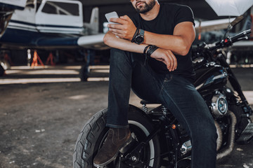 Plakat Caucasian man having rest in garage on his motorbike