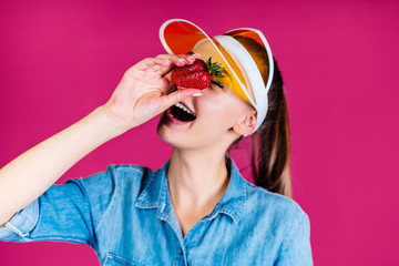 girl wants to determine by eye the size of strawberries. pink studio