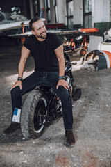 Fototapeta na wymiar Happy Caucasian guy sitting on motorbike in garage