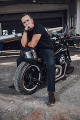 Caucasian man sitting on motorbike in garage