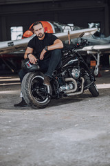 Fototapeta na wymiar Adult Caucasian man sitting on black modern motorbike