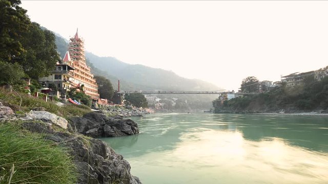 Stunning time lapse video of the Ganga river embankment with the Lakshman Jhula bridge and the Tera Manzil Temple (Trimbakeshwar) during a beautiful sunset. Rishikesh, Uttarakhand, India.