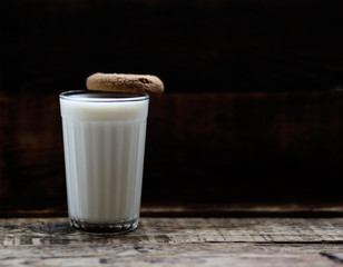 glass of milk cookies with chocolate chips on the background of wooden boards