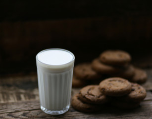 glass of milk cookies with chocolate chips on the background of wooden boards
