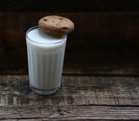 glass of milk cookies with chocolate chips on the background of wooden boards