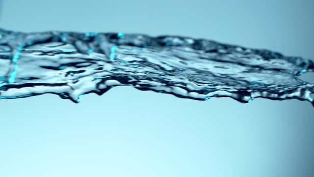 Super slow motion of flying water splash on soft blue background. Filmed on high speed cinema camera, 1000fps.