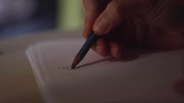 close up su mano che scrive una lettera con una matita su un foglio di carta