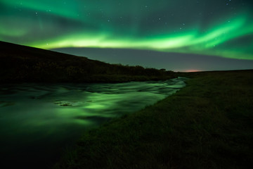 Northern lights with reflection in river, North Iceland