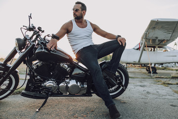 Handsome male biker resting on his motorbike